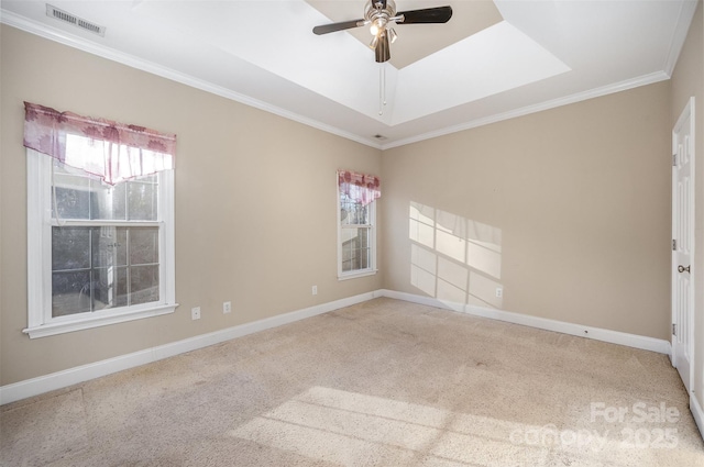 carpeted spare room with a tray ceiling, ceiling fan, and ornamental molding