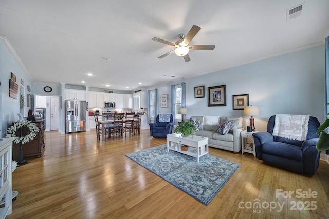 living room with ornamental molding, ceiling fan, and light hardwood / wood-style floors