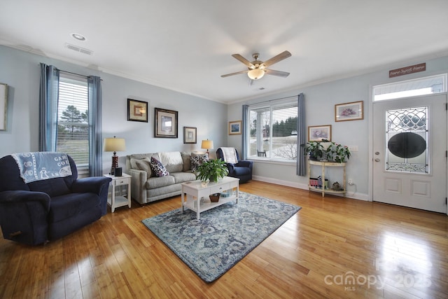 living room featuring ornamental molding, plenty of natural light, and light wood-type flooring