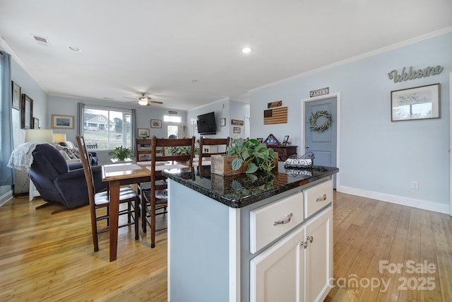 kitchen featuring white cabinetry, crown molding, light hardwood / wood-style flooring, and a kitchen island