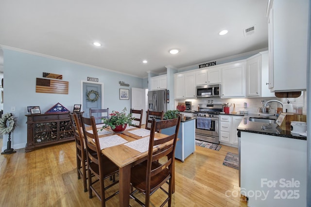 kitchen featuring sink, crown molding, appliances with stainless steel finishes, white cabinets, and light wood-type flooring