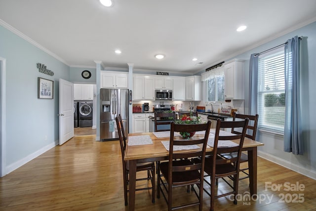 dining space with crown molding, washer / dryer, sink, and light wood-type flooring