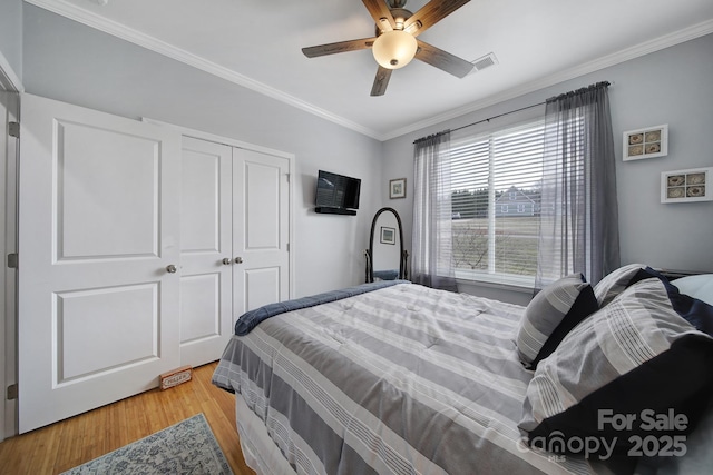 bedroom with hardwood / wood-style floors, crown molding, a closet, and ceiling fan