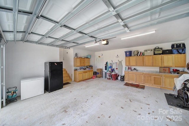 garage featuring black refrigerator, fridge, and a garage door opener