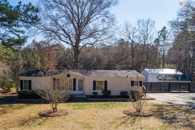 view of front facade featuring driveway, a front lawn, and fence