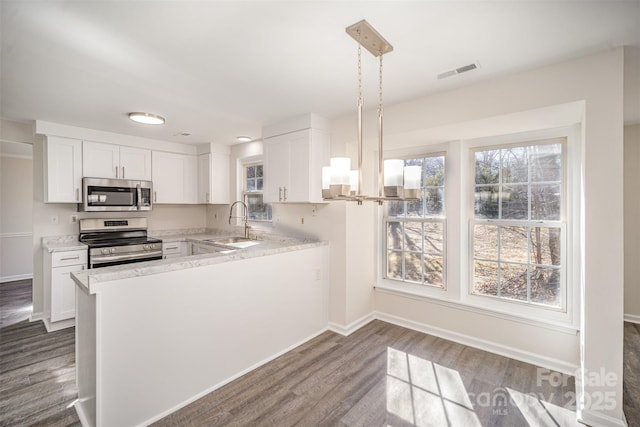 kitchen featuring white cabinetry, hanging light fixtures, kitchen peninsula, and appliances with stainless steel finishes