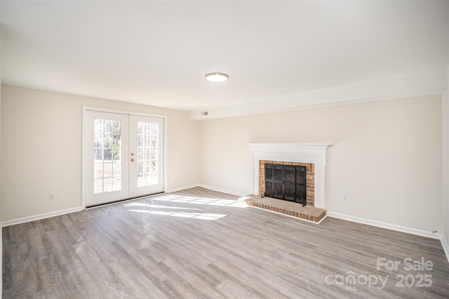 unfurnished living room with hardwood / wood-style flooring, a fireplace, and french doors