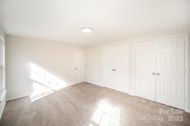 unfurnished bedroom with carpet and two closets