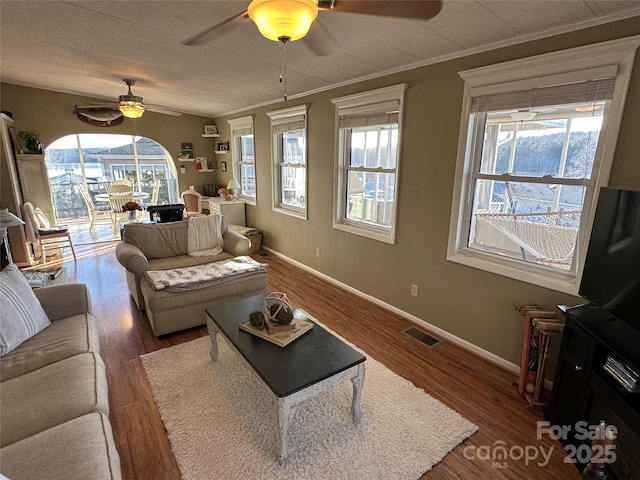 living room with ornamental molding, a healthy amount of sunlight, dark wood-type flooring, and ceiling fan