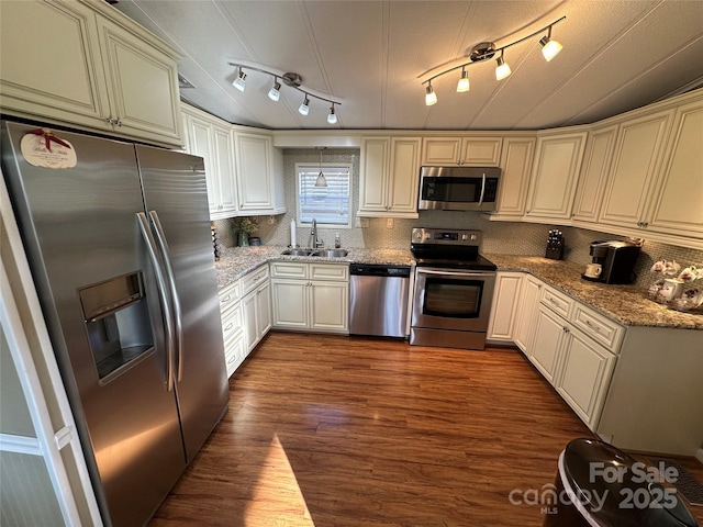 kitchen featuring sink, tasteful backsplash, stone countertops, appliances with stainless steel finishes, and hardwood / wood-style flooring