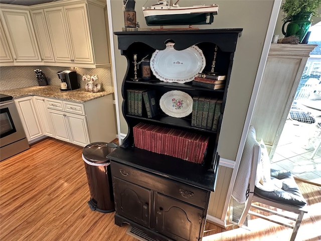 room details featuring light stone countertops, backsplash, light hardwood / wood-style floors, and electric stove