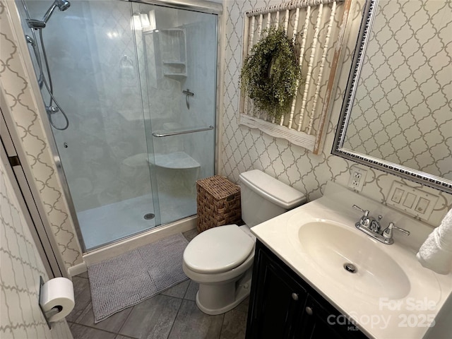 bathroom featuring vanity, a shower with door, and toilet