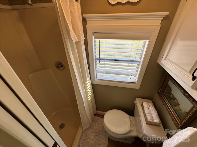 bathroom featuring toilet and curtained shower