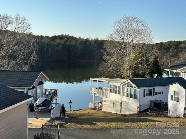 view of dock with a water view, a yard, and cooling unit