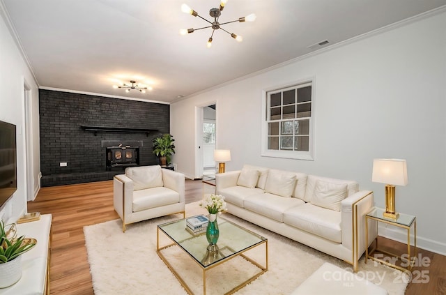 living room featuring crown molding, a wood stove, hardwood / wood-style floors, and a notable chandelier