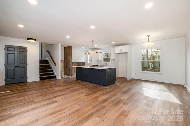 kitchen featuring white cabinetry, hanging light fixtures, a center island with sink, and a notable chandelier