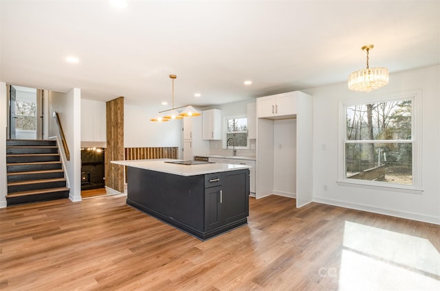 kitchen featuring hanging light fixtures, white cabinetry, a center island, and a notable chandelier