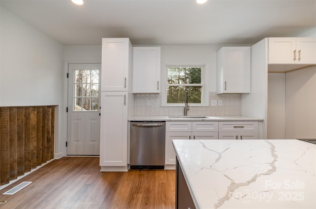 kitchen with white cabinetry, dishwasher, sink, light stone countertops, and light wood-type flooring