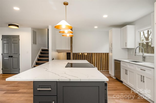 kitchen with stainless steel dishwasher, decorative light fixtures, a center island, and white cabinets