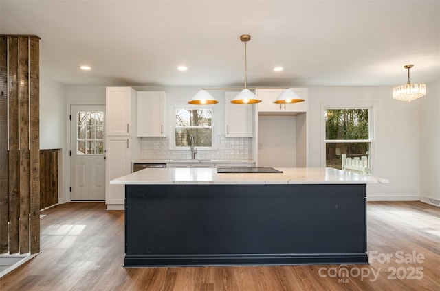 kitchen featuring sink, white cabinetry, a center island, tasteful backsplash, and decorative light fixtures