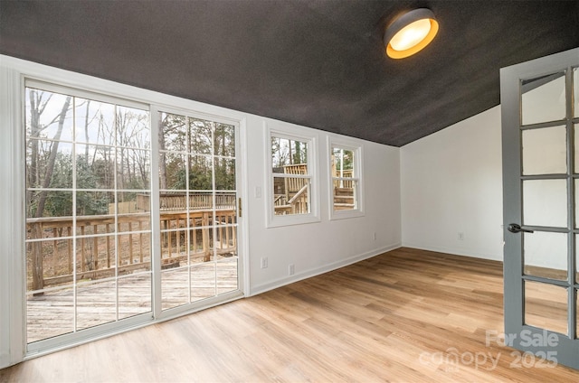 interior space featuring hardwood / wood-style flooring, vaulted ceiling, and a textured ceiling