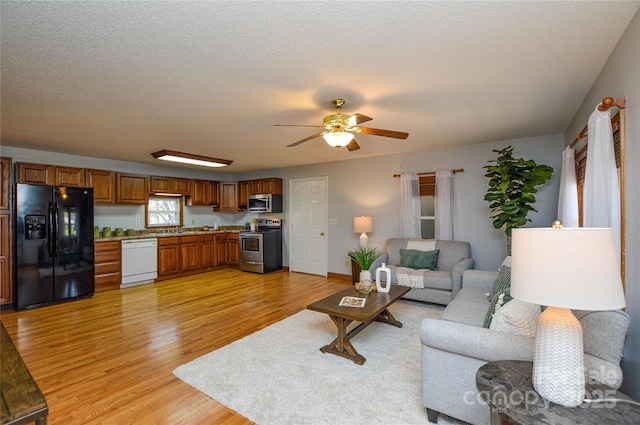 living room with sink, ceiling fan, a textured ceiling, and light wood-type flooring