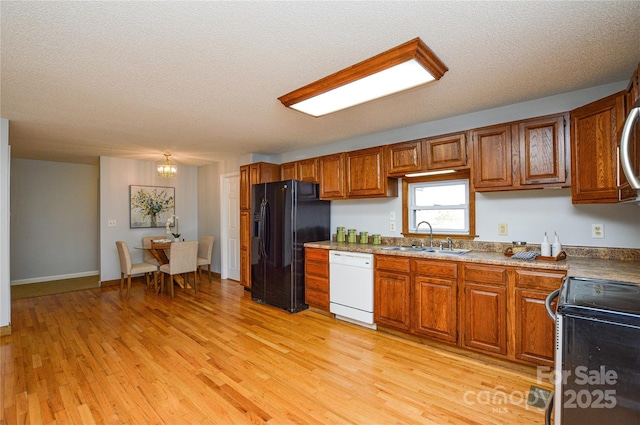 kitchen with white dishwasher, sink, black refrigerator with ice dispenser, and light hardwood / wood-style floors