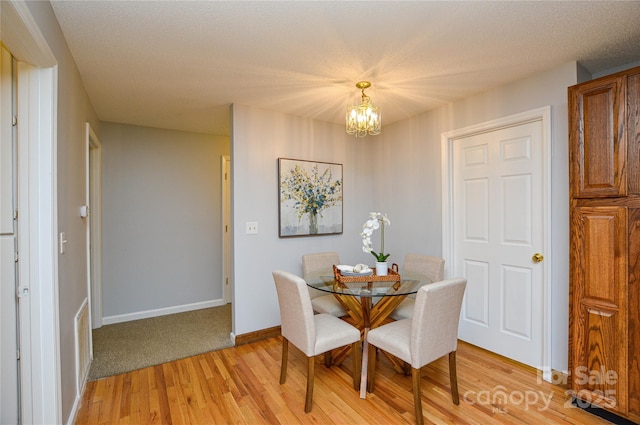 dining space featuring a textured ceiling, a chandelier, and light hardwood / wood-style flooring