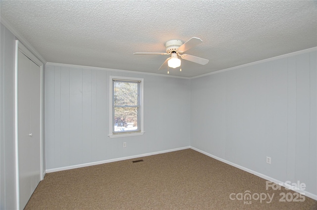 carpeted empty room featuring ornamental molding, a textured ceiling, and ceiling fan