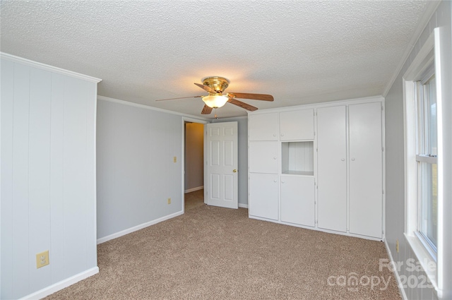 unfurnished bedroom featuring crown molding, ceiling fan, a textured ceiling, light colored carpet, and a closet