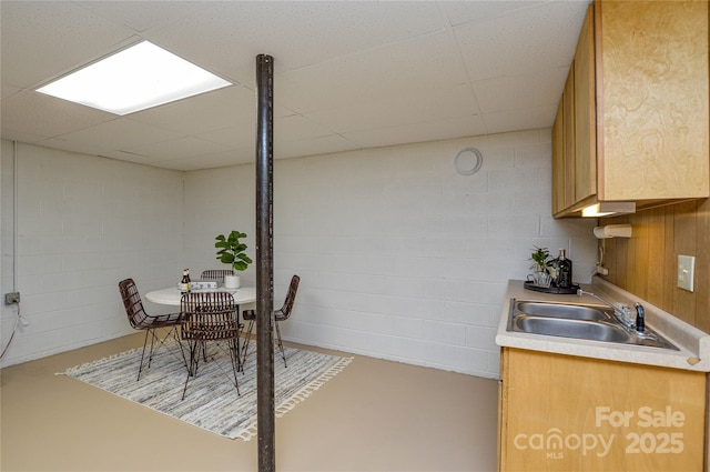 kitchen featuring a paneled ceiling, concrete flooring, and sink