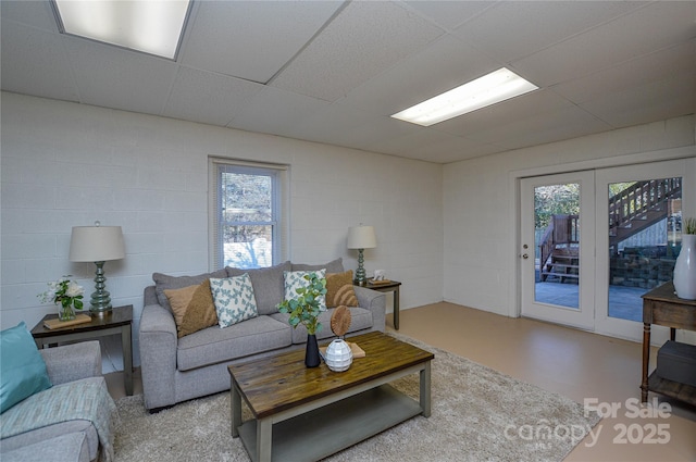 living room with a wealth of natural light, concrete floors, and a paneled ceiling