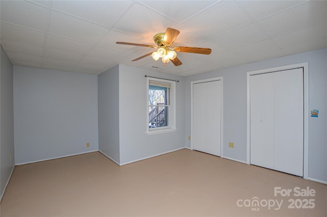 unfurnished bedroom with multiple closets, a paneled ceiling, and ceiling fan