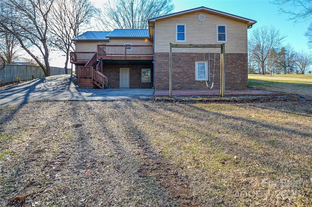 rear view of property with a deck, a patio area, and a lawn