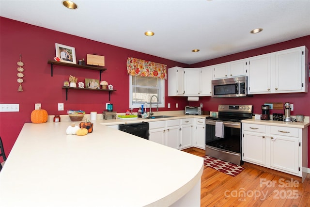 kitchen featuring sink, light wood-type flooring, kitchen peninsula, stainless steel appliances, and white cabinets