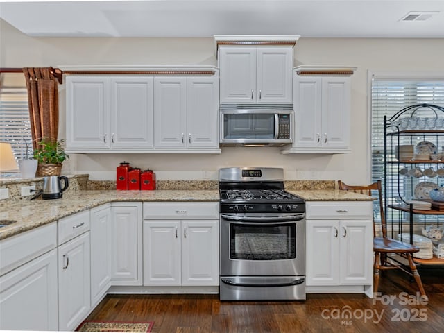 kitchen with light stone countertops, stainless steel appliances, dark hardwood / wood-style floors, and white cabinets