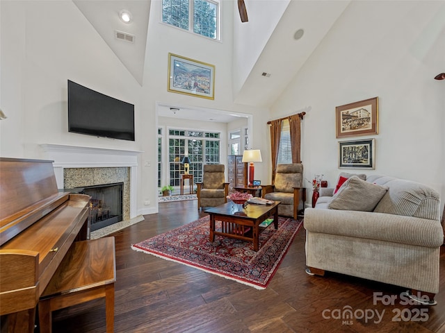 living room featuring dark hardwood / wood-style flooring, a fireplace, a towering ceiling, and plenty of natural light