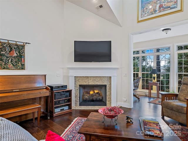 living room featuring dark wood-type flooring, a fireplace, and high vaulted ceiling