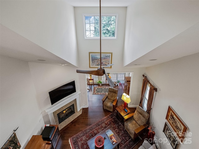 living room with a high ceiling, a tile fireplace, and dark wood-type flooring