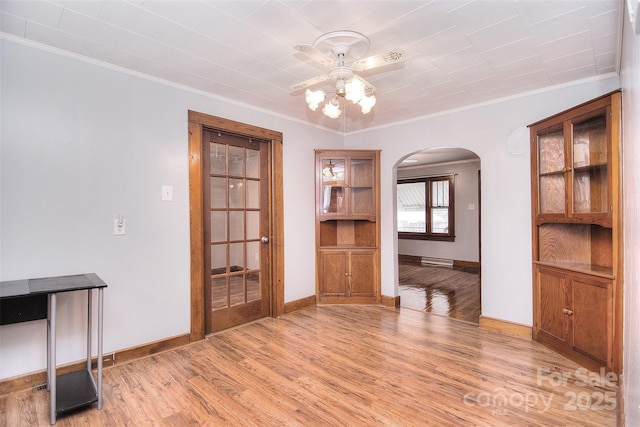 unfurnished dining area with ornamental molding, ceiling fan, and light wood-type flooring