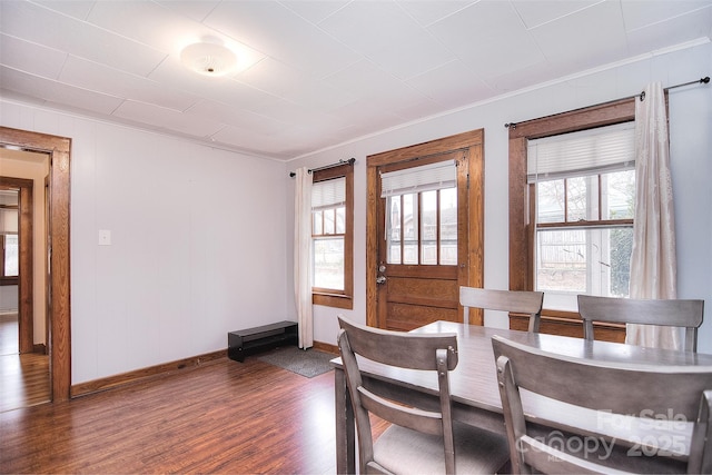 dining space with dark hardwood / wood-style flooring, crown molding, and a wealth of natural light