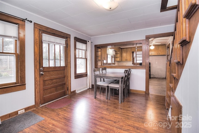 dining room with dark wood-type flooring, ornamental molding, and a healthy amount of sunlight