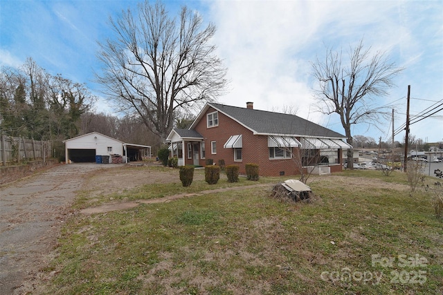 back of house featuring a garage, a carport, a yard, and an outbuilding