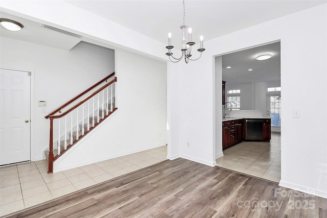 unfurnished dining area with sink, a chandelier, and light wood-type flooring