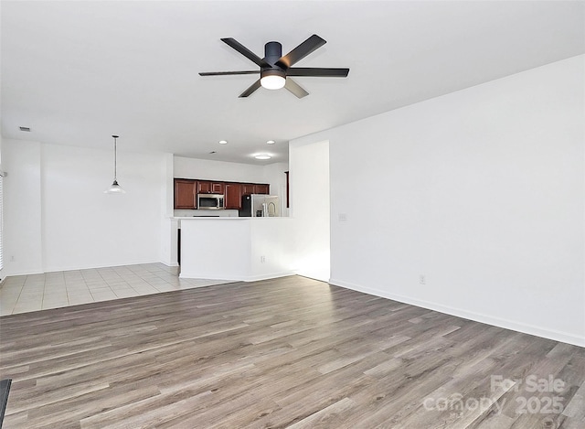 unfurnished living room featuring ceiling fan and light hardwood / wood-style floors