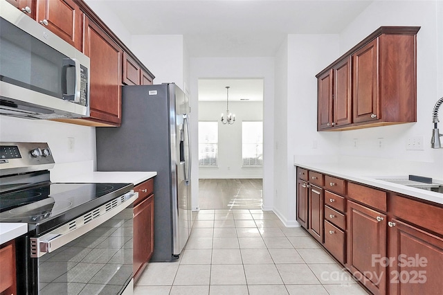 kitchen featuring pendant lighting, sink, appliances with stainless steel finishes, light tile patterned flooring, and a chandelier