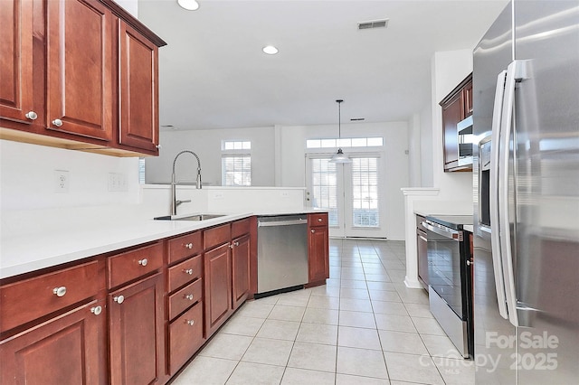 kitchen with light tile patterned flooring, sink, decorative light fixtures, appliances with stainless steel finishes, and kitchen peninsula