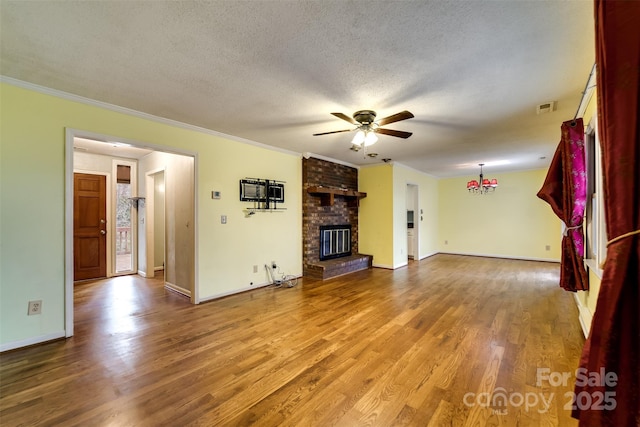 unfurnished living room featuring a fireplace, hardwood / wood-style flooring, ceiling fan, crown molding, and a textured ceiling