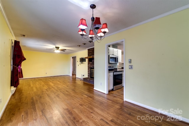 unfurnished living room featuring crown molding, a brick fireplace, hardwood / wood-style flooring, and ceiling fan with notable chandelier