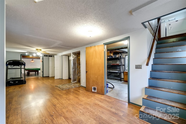 basement featuring ceiling fan, hardwood / wood-style flooring, and a textured ceiling